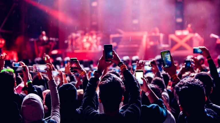personas disfrutando de un concierto y grabando con sus celulares. Por qué el ruido de conciertos puede causar pérdida auditiva irreversible